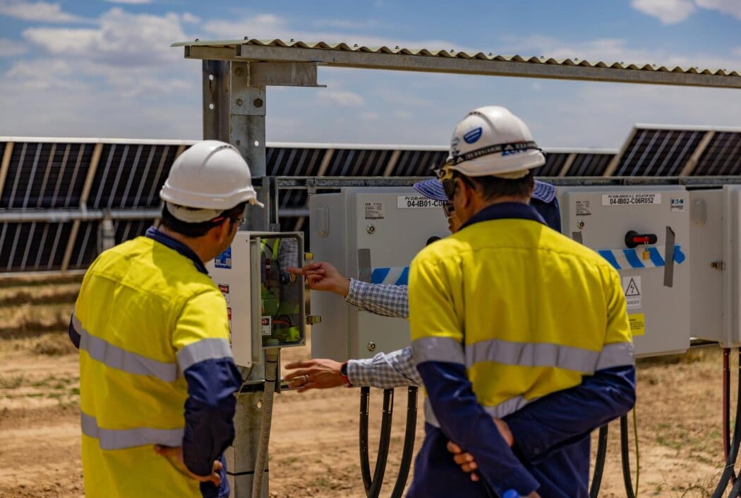 Personnel inspecting electrical equipment at a solar installation